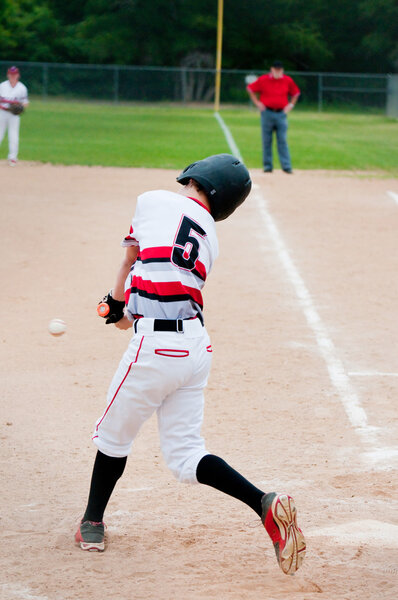 Молодой бейсболист бьет мяч
.