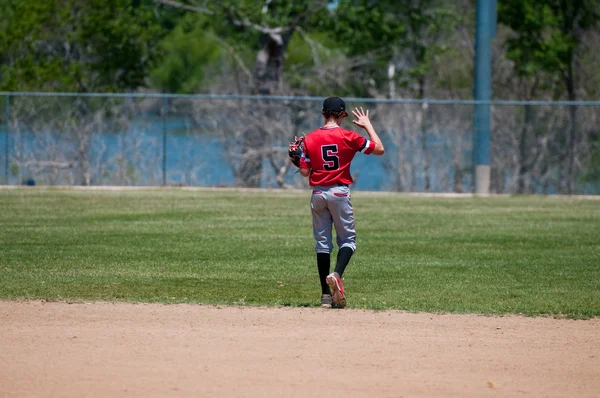Teenage baseball shortstop zezadu. — Stock fotografie