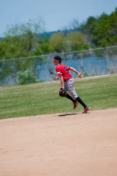 Teenage baseball shortstop běžící na poli. — Stock fotografie