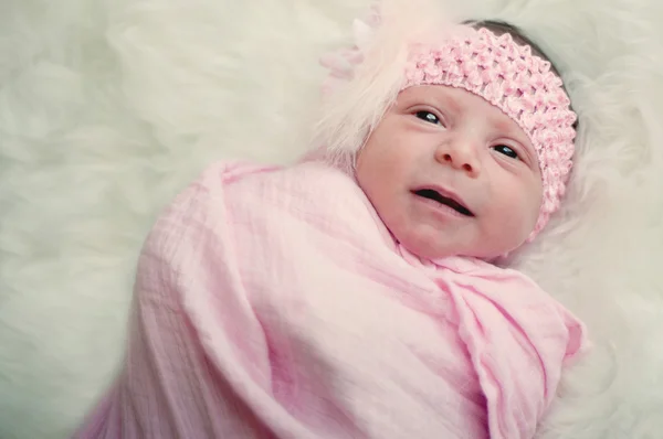Zamknij się z nowo narodzonego dziecka dziewczyna w różowym z wyrażenie zabawny. — Zdjęcie stockowe