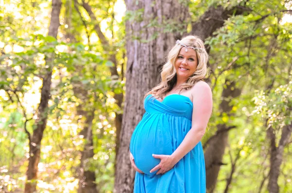 Beautiful pregnant woman in teal dress outdoors.