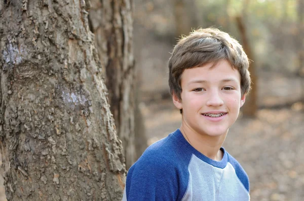 Mignon garçon souriant à côté de l'arbre — Photo