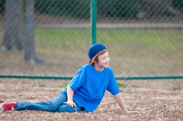 Junge mit Baseballmütze liegt im Gras lizenzfreie Stockfotos