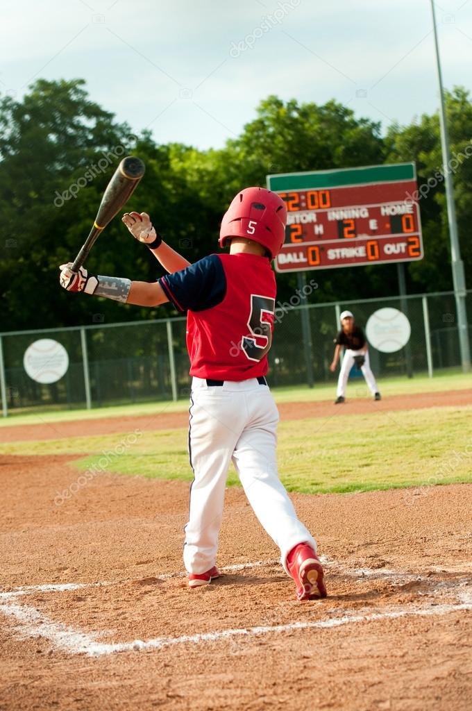 Young little league boy swings bat