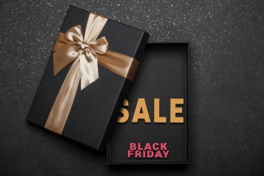 İçinde altın fiyonk ve yazı olan siyah hediye kutusunu aç. Kara Cuma indirimi. Hazır pankart tasarımı. Siyah granit arka plan