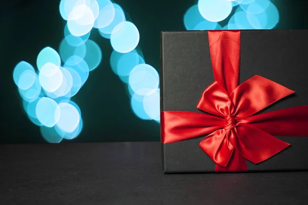 Μαύρο Κουτί Δώρου Κόκκινο Φιόγκο Στο Φόντο Μιας Μπλε Γιρλάντας — Φωτογραφία Αρχείου