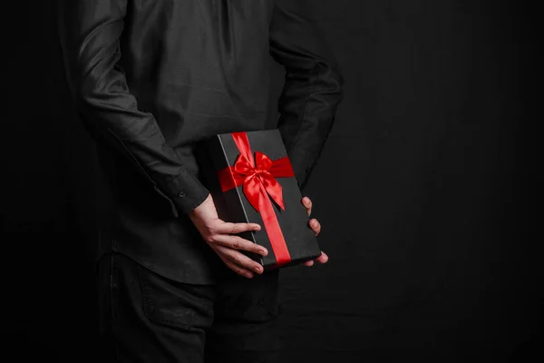 Άντρας Μαύρο Πουκάμισο Κρατάει Ένα Δώρο Μια Κόκκινη Κορδέλα Πίσω — Φωτογραφία Αρχείου