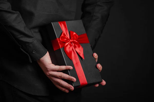 Hombre Con Una Camisa Negra Sostiene Regalo Con Una Cinta — Foto de Stock