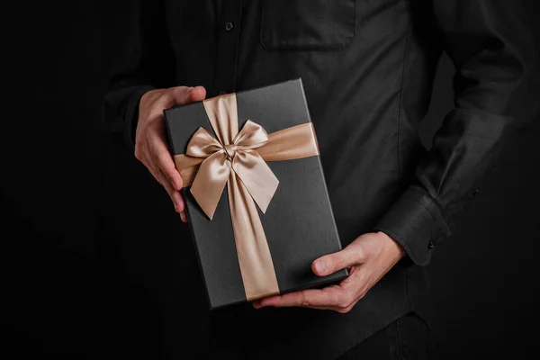 Guy Black Shirt Holding Gift Goldeb Ribbon Black Background Black — Stock Photo, Image