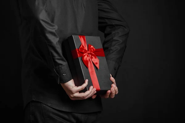 Hombre Con Una Camisa Negra Sostiene Regalo Con Una Cinta —  Fotos de Stock