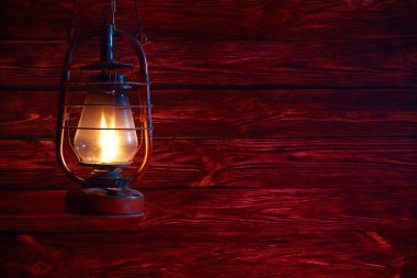 Ahşap arka planda taşınabilir bir gaz lambası. Kırmızı ahşap arka plan. Ateşten ışık.