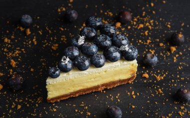 Tahta arka planda yaban mersinli cheesecake dilimi. Yukarıdan gelen dutlarla süslenmiş bir turta..