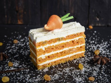 Siyah arka planda kremalı havuçlu kek ve havuç..