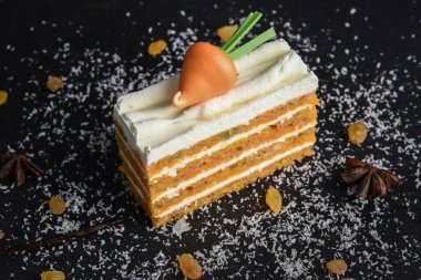 Siyah arka planda kremalı havuçlu kek ve havuç..