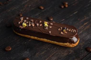 Çikolata jöleli, çikolatayla süslenmiş, yenebilir folyo parçalarıyla süslenmiş. Kahve çekirdekleri ile ahşap bir arka planda eklem..
