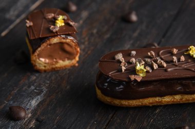 Çikolata jöleli, çikolatayla süslenmiş, yenebilir folyo parçalarıyla süslenmiş. Ahşap bir arka planda, içinde kahve taneleri ve dolgu malzemesi olan bir kesikte eklem..