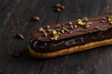 Çikolata jöleli, çikolatayla süslenmiş, yenebilir folyo parçalarıyla süslenmiş. Kahve çekirdekleri ile ahşap bir arka planda eklem..