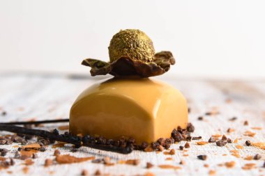 Çikolatayla süslenmiş karamelli şekerleme ve yenilebilir altınla kaplı bir top. Hafif ahşap arka planda tatlılık.