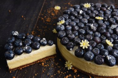 Bir dilim yabanmersinli cheesecake ve yanında büyük bir pasta. Yabanmersinli turta.