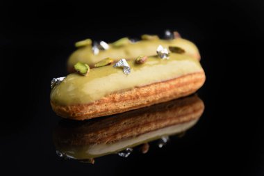 Yeşil jöleli, şam fıstığı ve yenilebilir folyoyla dekore edilmiş siyah bir arka planda eklem..