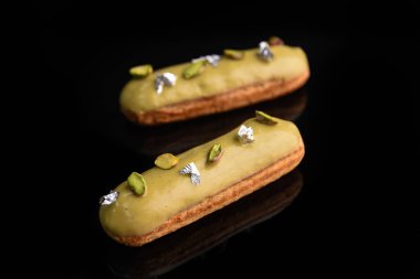 Yeşil jöleli, şam fıstığı ve yenilebilir folyoyla dekore edilmiş siyah bir arka planda eklem..