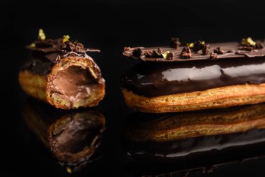 Siyah arka planda çikolataya doldurulmuş ekler..