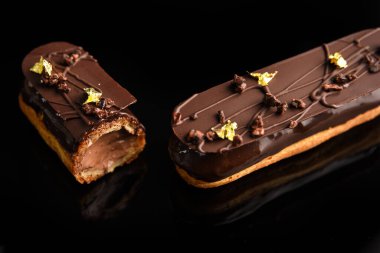 Siyah arka planda çikolataya doldurulmuş ekler..