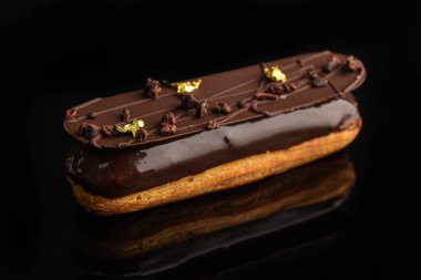 Çikolata jöleli ekler çikolata ve yenilebilir folyo kırıntılarıyla süslenmiş..