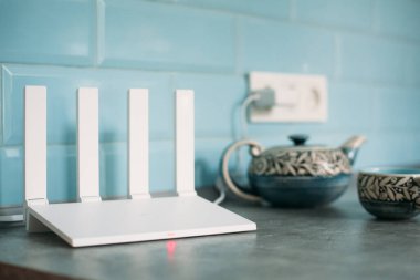 Beyaz Wi-Fi 6 yönlendirici mavi karo ve çaydanlığın arka planına karşı.