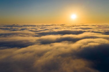 Güneşin doğuşunda beyaz kabarık bulutların yukarıdan görünüşü 
