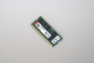 Yeşil DDR5 ECC bellek çubuğuna yakın plan etiketli ve QR kodlu, sade beyaz yüzey üzerinde izole edilmiş.