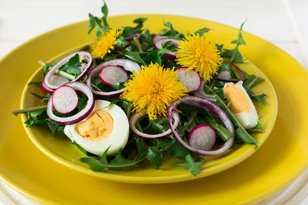 Fresh green dandelion salad on yellow plate — Stock Photo, Image