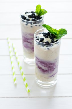 İki bardak taze yaban mersini dekore edilmiş smoothie çilek ve nane yaprakları ile. Seçici odak