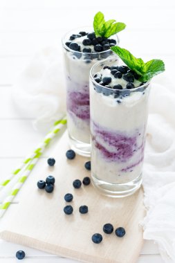 İki bardak taze yaban mersini dekore edilmiş smoothie çilek ve nane yaprakları ile. Seçici odak