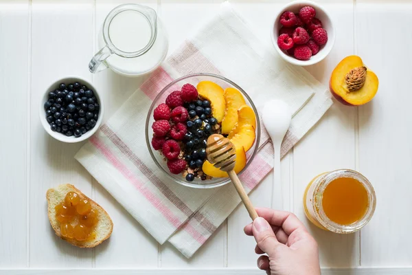 Здоровый завтрак: мюсли с медом, молоком и свежими ягодами в миске — стоковое фото