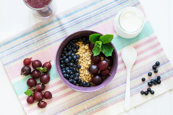 Café da manhã saudável: muesli com groselha espinhosa e amora, iogurte, smoothie de mirtilo e muffins de chocolate — Fotografia de Stock