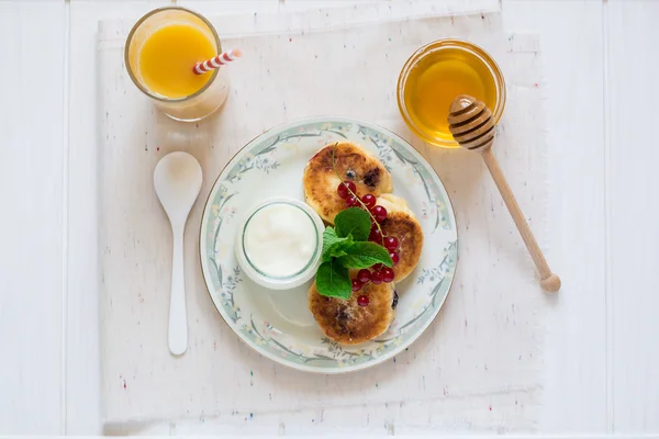 Desayuno saludable: tartas de queso, muesli, yogur, miel, bayas frescas y jugo — Foto de Stock