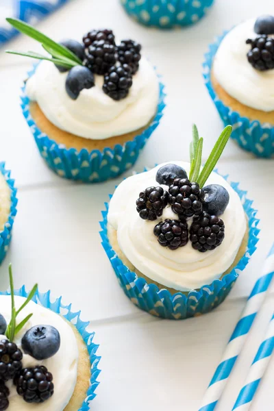 Cupcakes caseiros com cobertura, mirtilos, amoras e folhas de alecrim — Fotografia de Stock