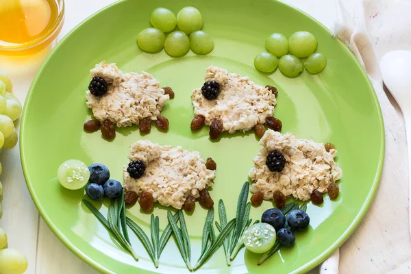 Baby healthy breakfast: oatmeal sheeps decorated berries — Stock Photo, Image