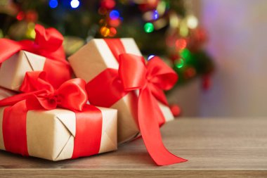 Noel ağacına karşı büyük kırmızı fiyonklu hediye kutuları ve çözülmüş bokeh. Yumuşak odaklanma. Uzayı kopyala Noel kutlaması konsepti