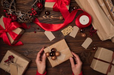 Kahverengi ahşap masa üzerinde hediye paketi yapan kadın eller. Üst Manzara. Yeni yıl ya da Noel kutlaması konsepti