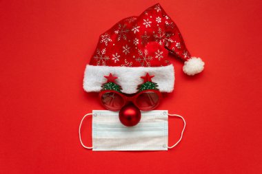 Noel Baba şapkası, gözlük ve kırmızı arka planda yüz maskesi olan bir burun. Düz yatıyordu. Noel veya Yeni Yıl Kutlama Konsepti