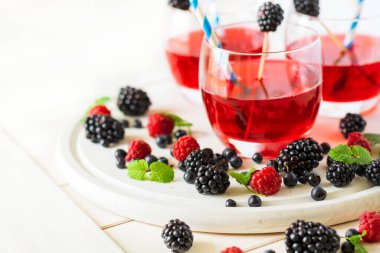 Beyaz ahşap masada ahududu ve böğürtlenli yaz içeceği. Yumuşak odak