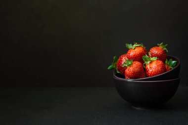 Koyu arkaplanda taze olgun çilekler. Boşluğu kopyala