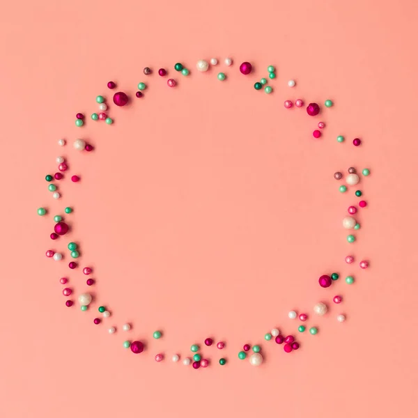 Circle wreath shape made of colorful sprinkling on pink background.  Easter celebration concept. Top view.