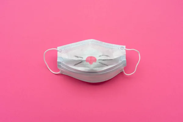 Protective mask with painted nose on pink background. Covid Easter holiday concept