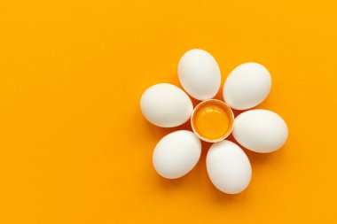 Beyaz yumurta ve yumurta sarısından çiçekli yumurta sarısı sarı ve gri arka planda yuvaya dönüşür. Üst Manzara. Düz yatıyordu. Paskalya kutlaması