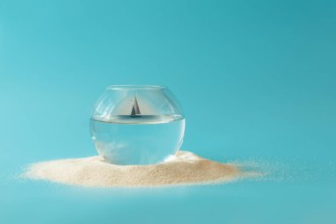 Mavi arka planda yelkenli olan akvaryum. Yaratıcı yaz tatili konsepti