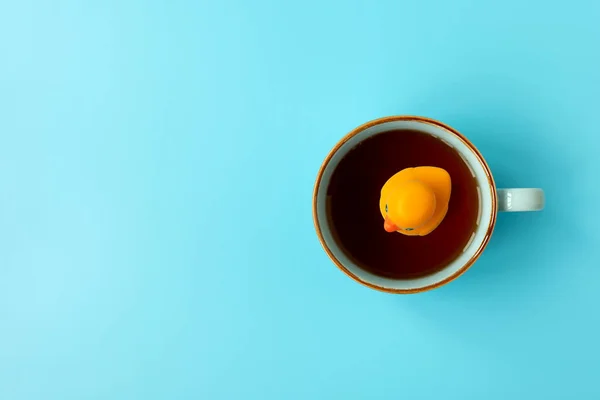 Желтая Резиновая Утка Плавающая Чашку Чая Синем Фоне Творческая Концепция — стоковое фото