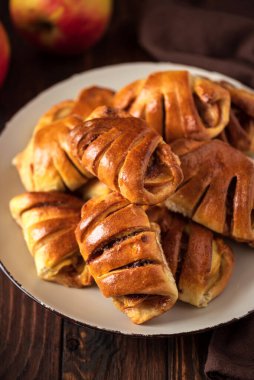 Kahverengi ahşap arka planda elma ve tarçınlı ev yapımı çörekler. Yumuşak odak